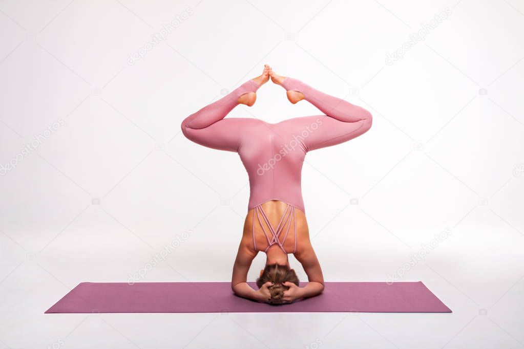 Young sporty woman in pink jumpsuit practicing yoga, isolated on white background