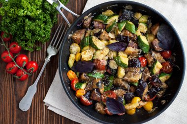 Sebze Fırında kabak, patlıcan, domates, baharat ve tavada ahşap masa üzerinde taze fesleğen üzerinden