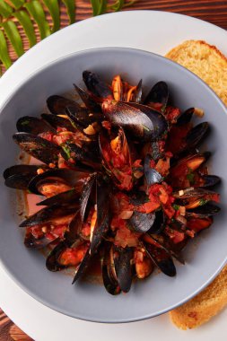 Deniz ürünleri, domates ve soğan saice baget ahşap masa üzerinde kase ile midye