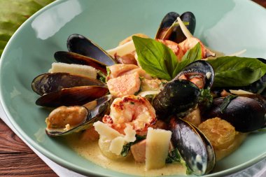 Çeşitli deniz ürünleri, midye, mürekkep balığı, tarak, somon fileto ve kaplan karides fesleğen sarımsak kremalı sos, parmesan peyniri ile