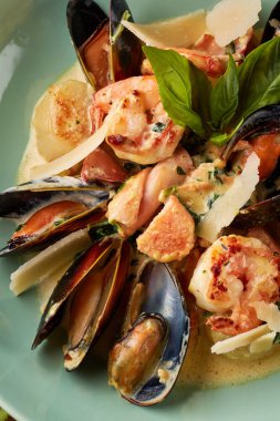 Çeşitli deniz ürünleri, midye, mürekkep balığı, tarak, somon fileto ve kaplan karides fesleğen sarımsak kremalı sos, parmesan peyniri ile