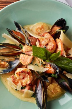 Çeşitli deniz ürünleri, midye, mürekkep balığı, tarak, somon fileto ve kaplan karides fesleğen sarımsak kremalı sos, parmesan peyniri ile