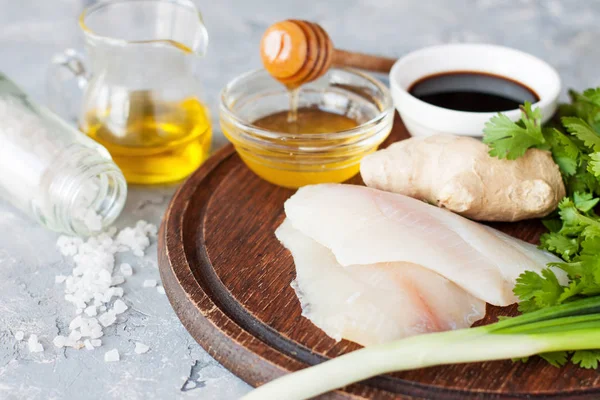 生罗非鱼鱼片 酱油和调味品上的木制切菜板 香丝焦糖生姜和香葱蒸白鱼的成分 — 图库照片