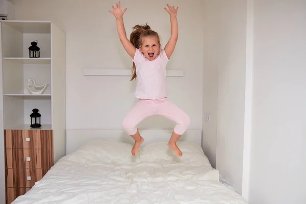 Смеющаяся Маленькая Девочка Прыгающая Большой Белой Кровати Развлекающаяся Выходным Утром — стоковое фото