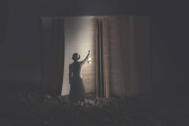 Meraklı kadın bir fener ile dev bir kitap geceleri yanar