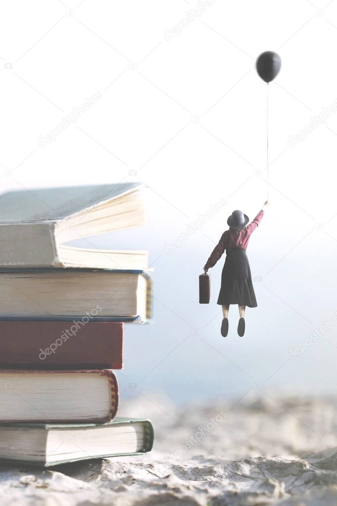 woman carried by a balloon flies above a mountain of giant books