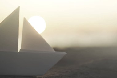 origamo tekne güneş tarafından aydınlatılmış kayalar üzerinde yelken