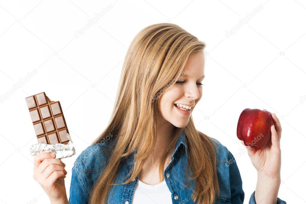 Girl holding an apple and a chocolate in her hands