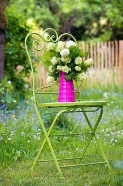 Romantik bir bahçede çiçekli bahçe sandalyesi