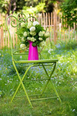 Romantik bir bahçede çiçekli bahçe sandalyesi