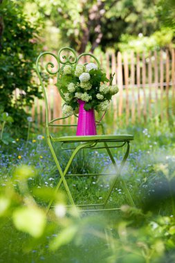 Romantik bir bahçede çiçekli bahçe sandalyesi