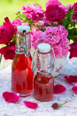Bahçe masasında gül suyu şişeleri