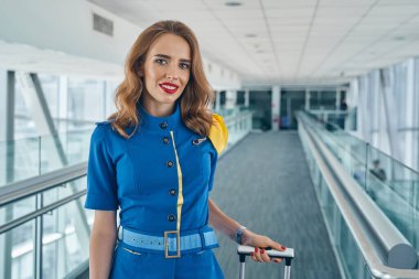 Modern bir uçuş görevlisi havaalanı terminalinde duruyor.