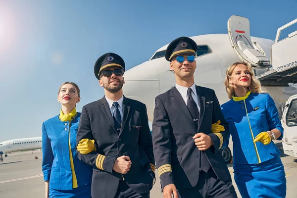 Pleased airmen and female flight attendants standing outdoors — Stock Photo, Image