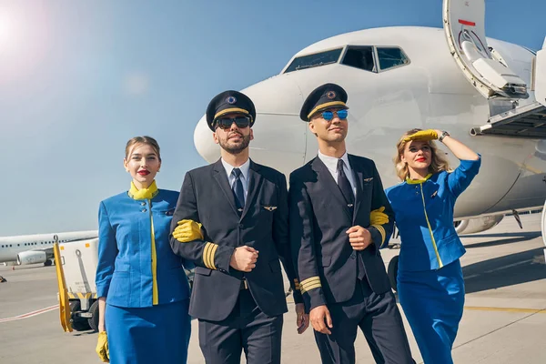Elegant pilots and slim stewardesses looking ahead — Stock Photo, Image