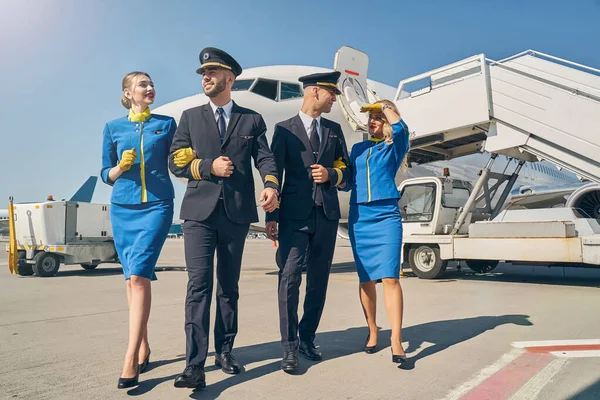 Glimlachende blonde stewardessen en piloten in een zonnebril — Stockfoto
