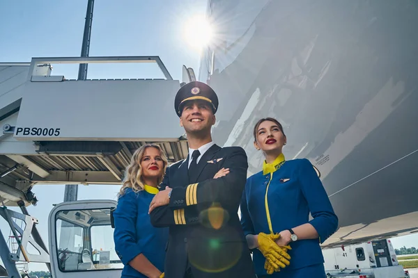 Handsome airman and smiling flight attendants looking up — Stock Photo, Image