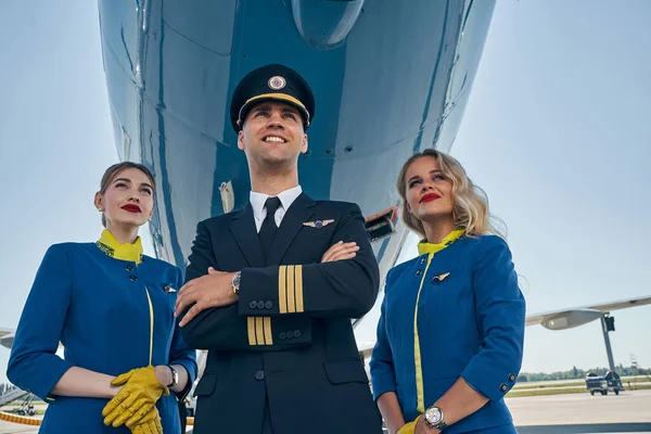 Two beautiful stewardesses and an airman staring ahead — Stock Photo, Image