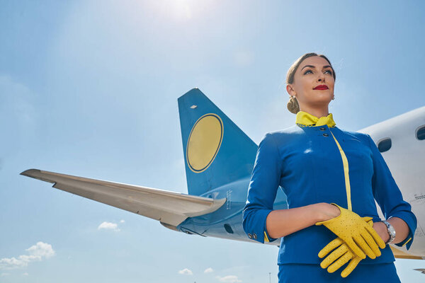 Serene young stewardess against the blue sky
