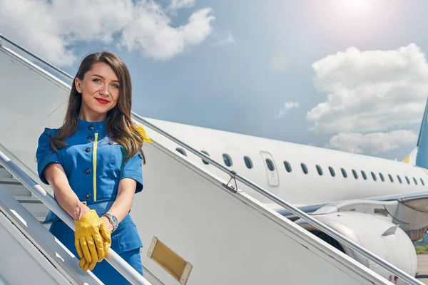 Sonriente azafata elegante de pie en las escaleras de los aviones — Foto de Stock