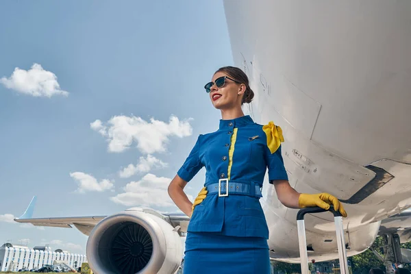 Веселая стюардесса, стоящая у самолета — стоковое фото