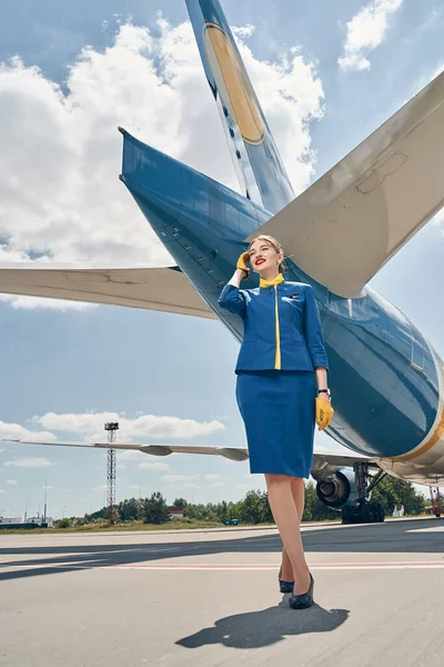 Радостная элегантная стюардесса перед самолетом — стоковое фото
