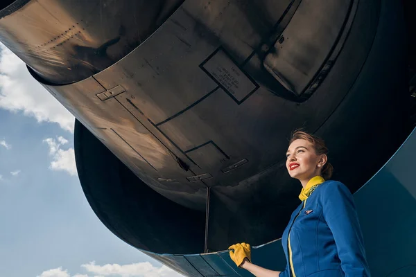 Usmívající se atraktivní letuška dívá před sebe — Stock fotografie