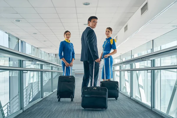 Élégant steward et hôtesses heureuses avec valises — Photo