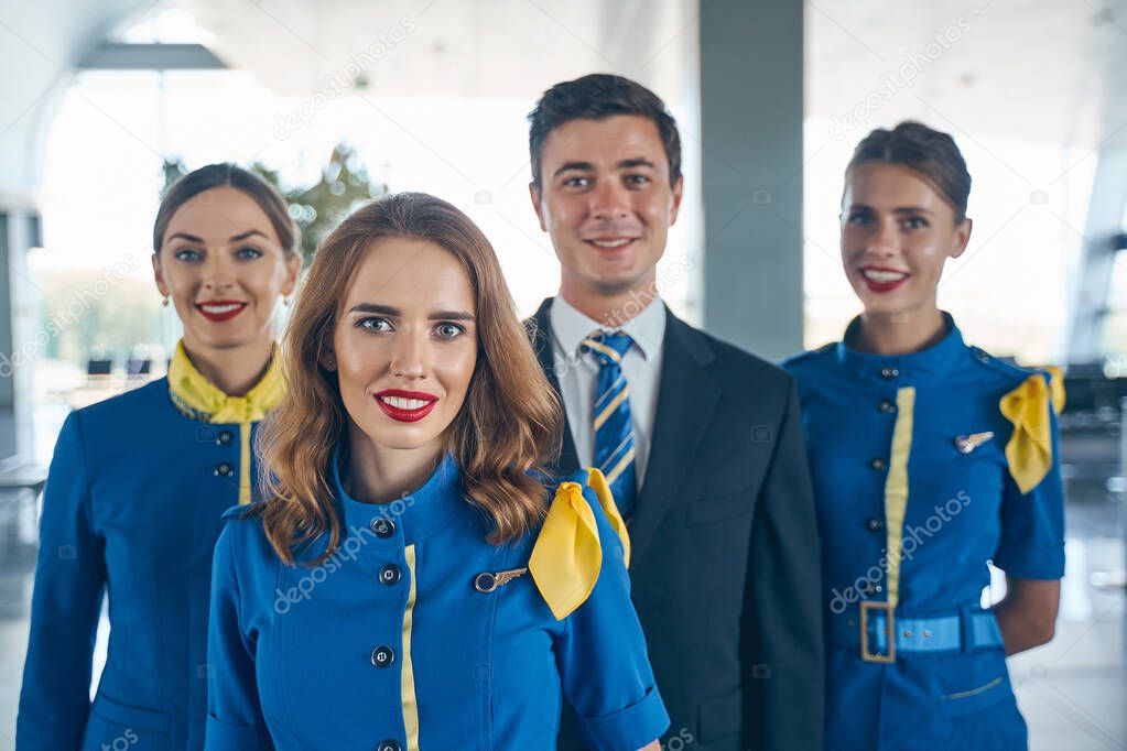 Handsome steward and female flight attendants looking forward