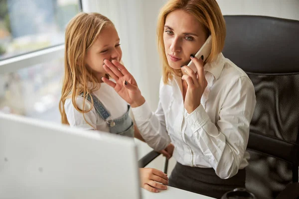 Little girl needing care and attention from mother while standing in the office — Stock Photo, Image