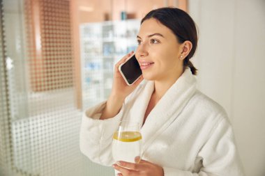 Geleceğe bakan akıllı telefonlu neşeli bir spa müşterisi