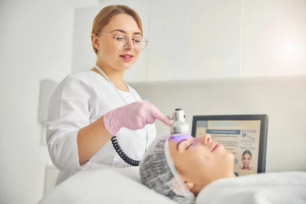 Dermatologin richtet ein Foto-Schönheitsgerät an ihre Kundin — Stockfoto