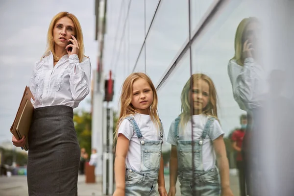 Ritratto di bella donna che tiene la cartella con i documenti in mano mentre cammina con la figlia in città — Foto Stock