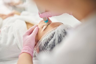 Genç beyaz kadın dermatolojik bir prosedür geçiriyor.