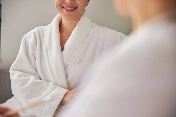 Счастливый клиент спа сидит рядом с косметологом