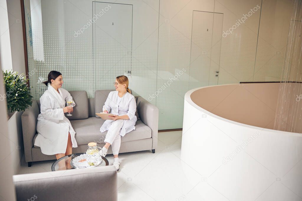 Dark-haired patient and a blonde doctor smiling at each other