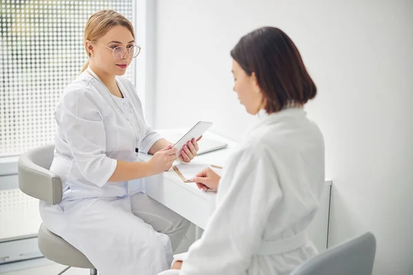 Femme attentive médecin à l'écoute de son client — Photo