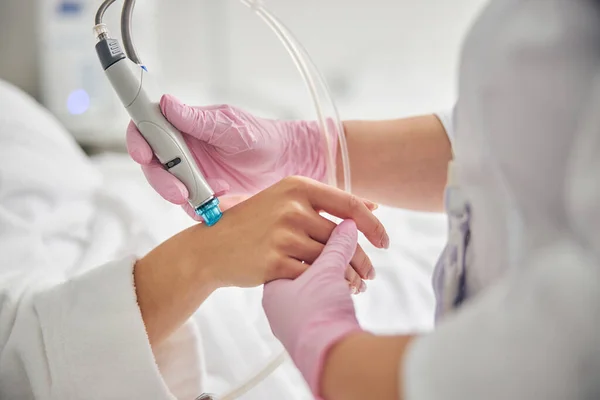Läkare i sterila handskar med hjälp av en dermabrasion anordning — Stockfoto