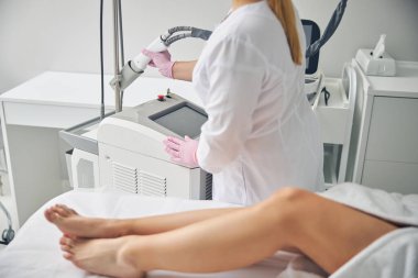 Dermatolog lazer tüy temizleme cihazına uzanıyor.