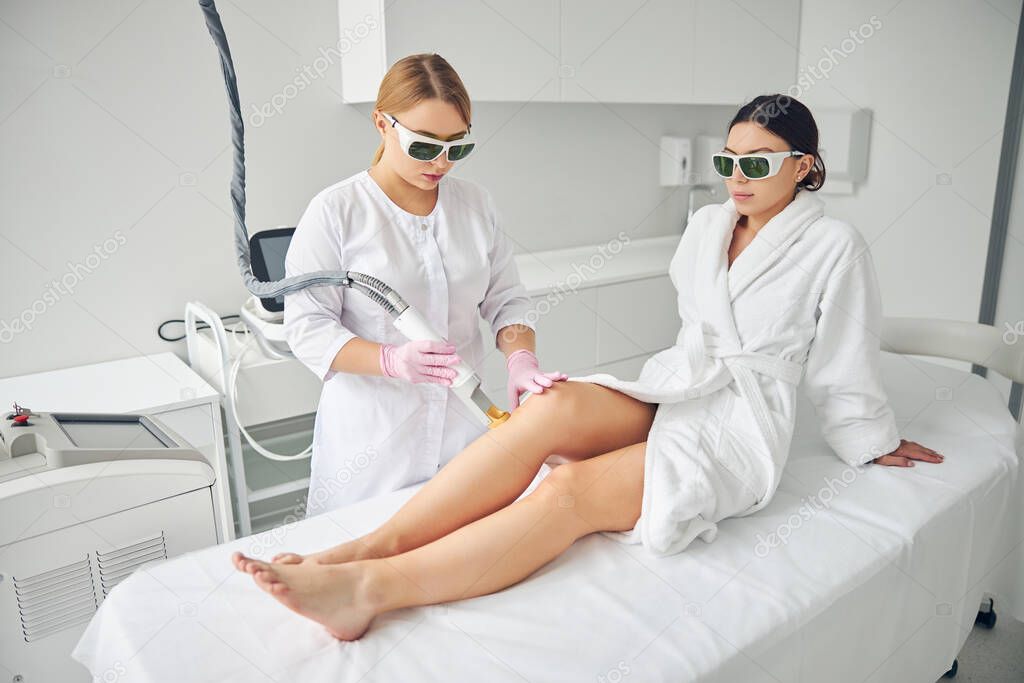 Professional cosmetologist performing the laser hair removal