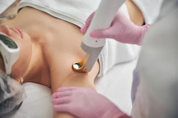 皮肤科医生将集中的激光束对准她的病人腋窝 — 图库照片