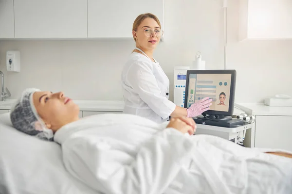 Pleased cosmetologist in eyeglasses posing for the camera — Stock Photo, Image