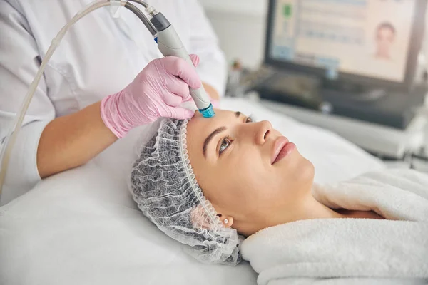 Young female patient undergoing a hydrodermabrasion treatment — Stock Photo, Image