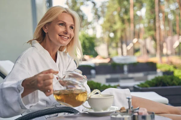 Mooie vrouw is ontspannen in een badjas — Stockfoto