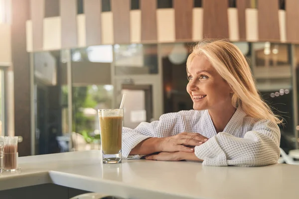 Vrolijke dame aan de bar met een glas sap — Stockfoto