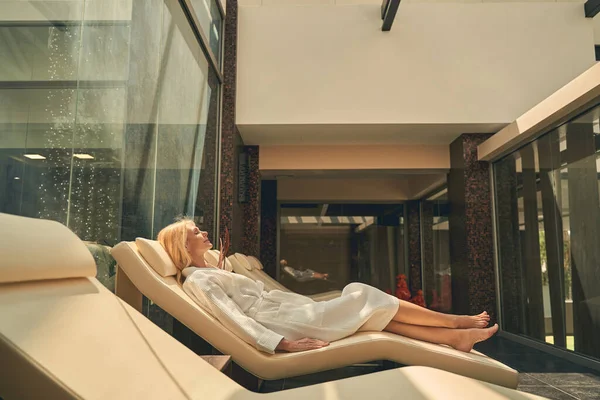 Gelassene Frau entspannt sich nach Wellness-Eingriff im Ruheraum — Stockfoto