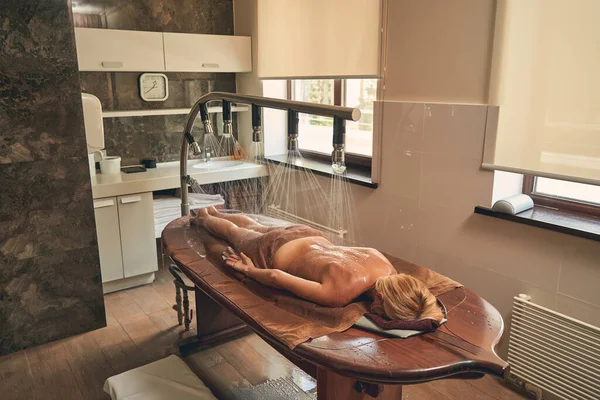 Femme couchée sur le lit en bois dans la salle de spa de l'hôtel station balnéaire — Photo