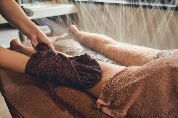Жінка лежить на дерев'яному столі, маючи дощ для душу і масаж на ногах — стокове фото