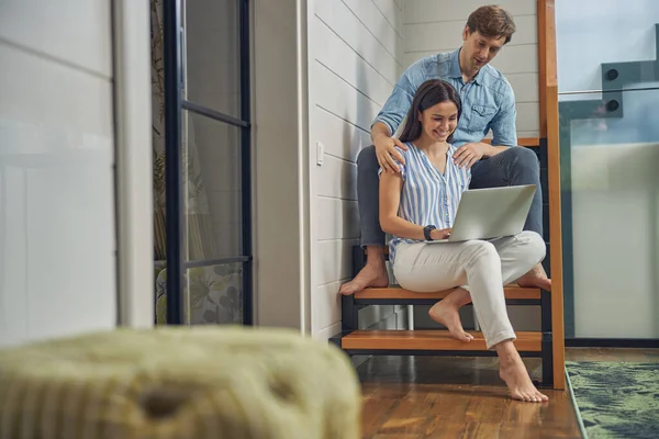 Pareja joven relajándose en una lujosa casa con computadora — Foto de Stock