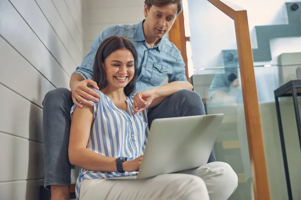 Bastante sonriente dama con hombre guapo viendo algo en el portátil — Foto de Stock